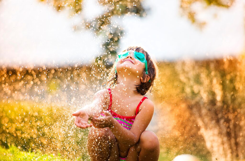 kid playing with sprinklers outside