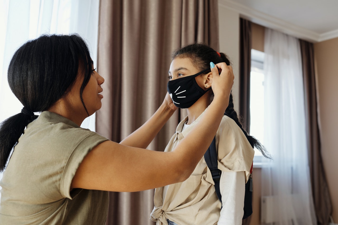 Mother helping daughter wear face mask